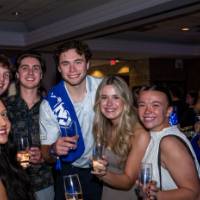 Group of grads smile with champagne glasses at Toast